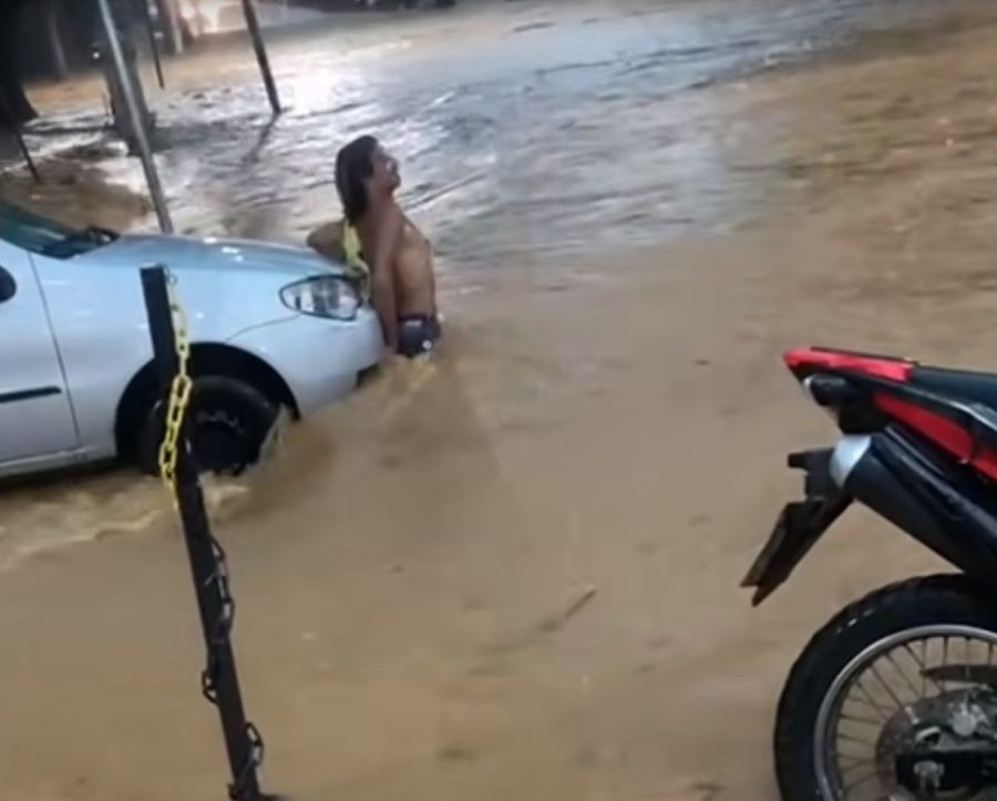 Enxurrada invade Cataguases e homem se segura em veículo para escapar da força da água